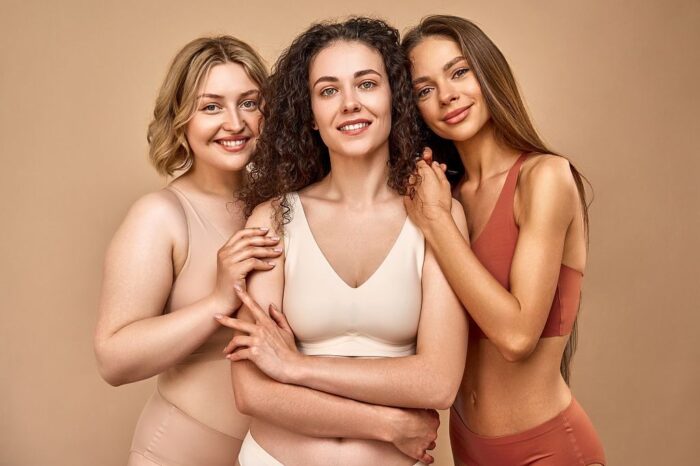 The power of women.Three different women in underwear are looking at the camera and smiling. In the middle, a curly-haired woman stands with her arms crossed, on the sides a blonde and a brunette.