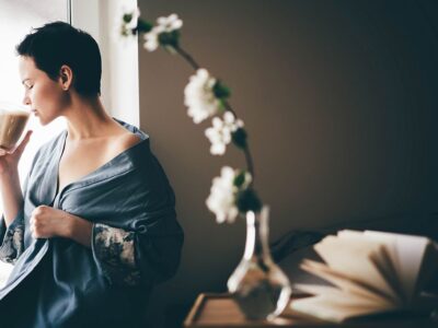 Beautiful woman in blue pajamas having breakfast in bed in morning. Girl drinking coffee.